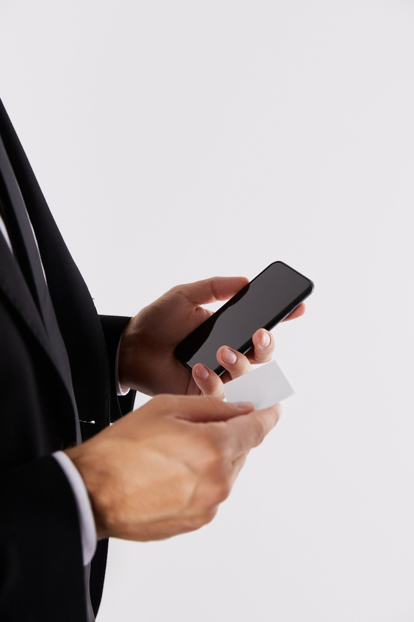 cropped image of businessman holding empty business card and smartphone with blank screen isolated